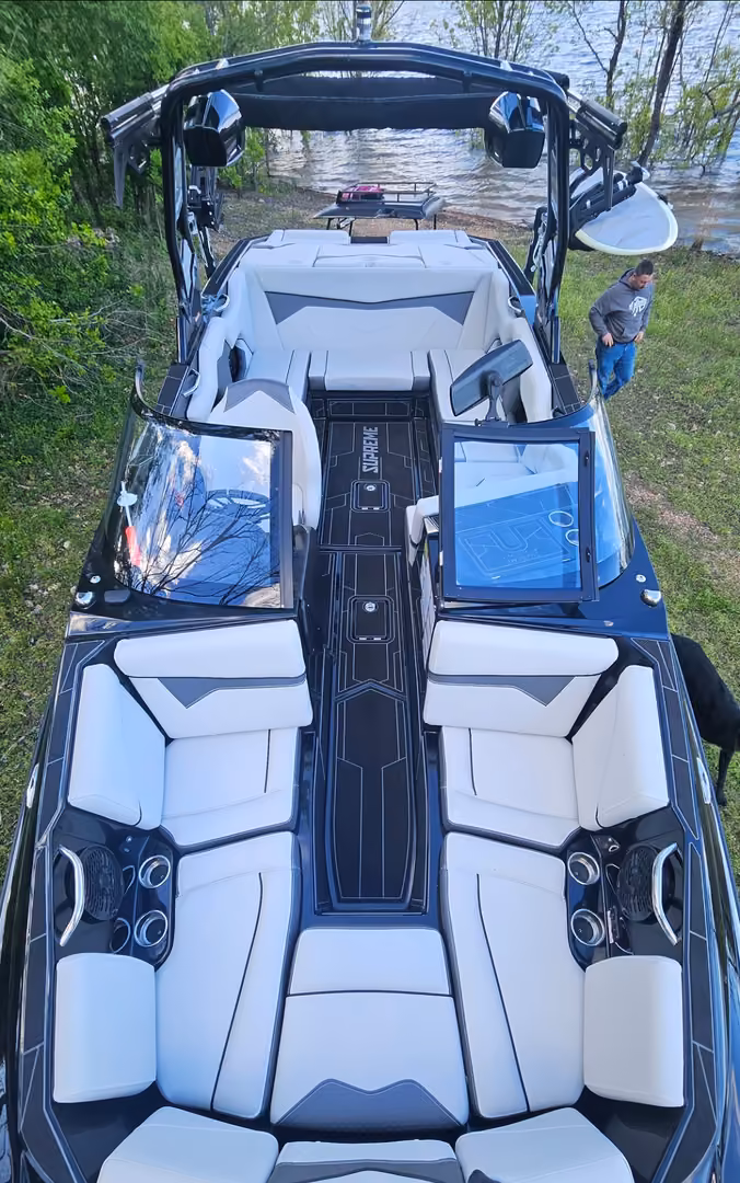 The whole cockpit from above, tower to bow: white seating, the Supreme deck mat and both windshields.